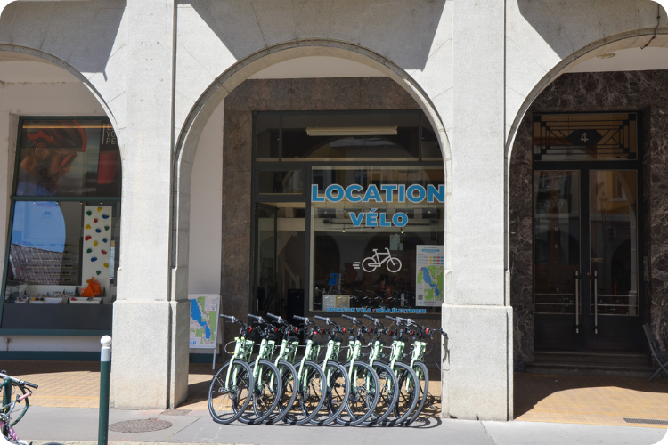 Devanture Mobilboard « Location Vélo » à Annecy avec une rangée de vélos sous les arcades